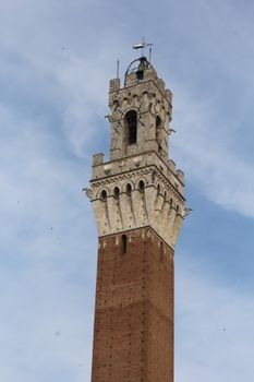 Close-up of Torre del Mangia in Siena, showcasing its Renaissance architecture under a blue sky.