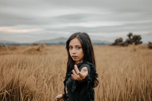 Young Woman in Field Stretching Hand to Camera