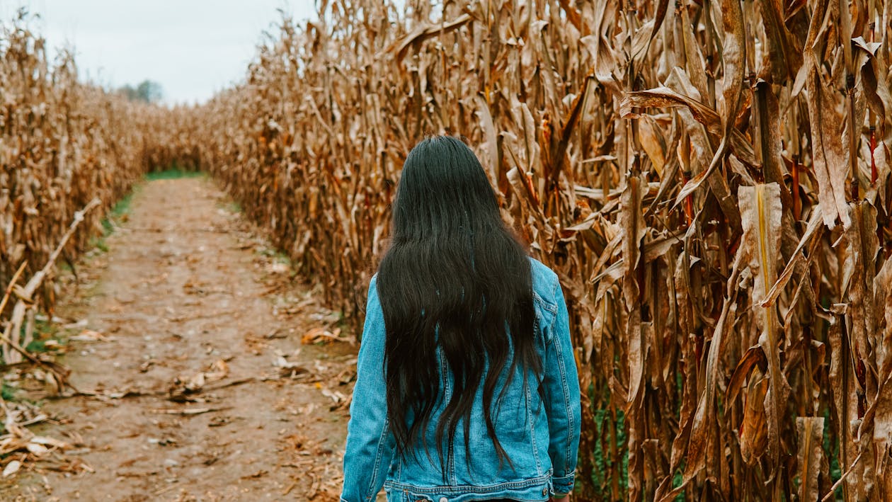 Free Woman in Blue Denim Jacket Standing on Brown Dirt Road Stock Photo