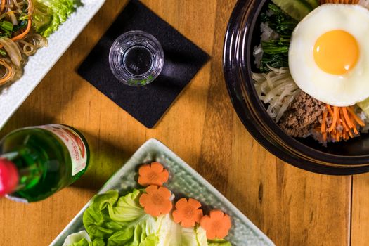 Traditional Korean bibimbap with fresh ingredients and classic sides, captured from above.