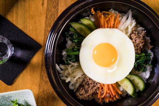 Delicious Korean Bibimbap dish featuring a fried egg, fresh vegetables, and savory beef, perfect for lunch or dinner.