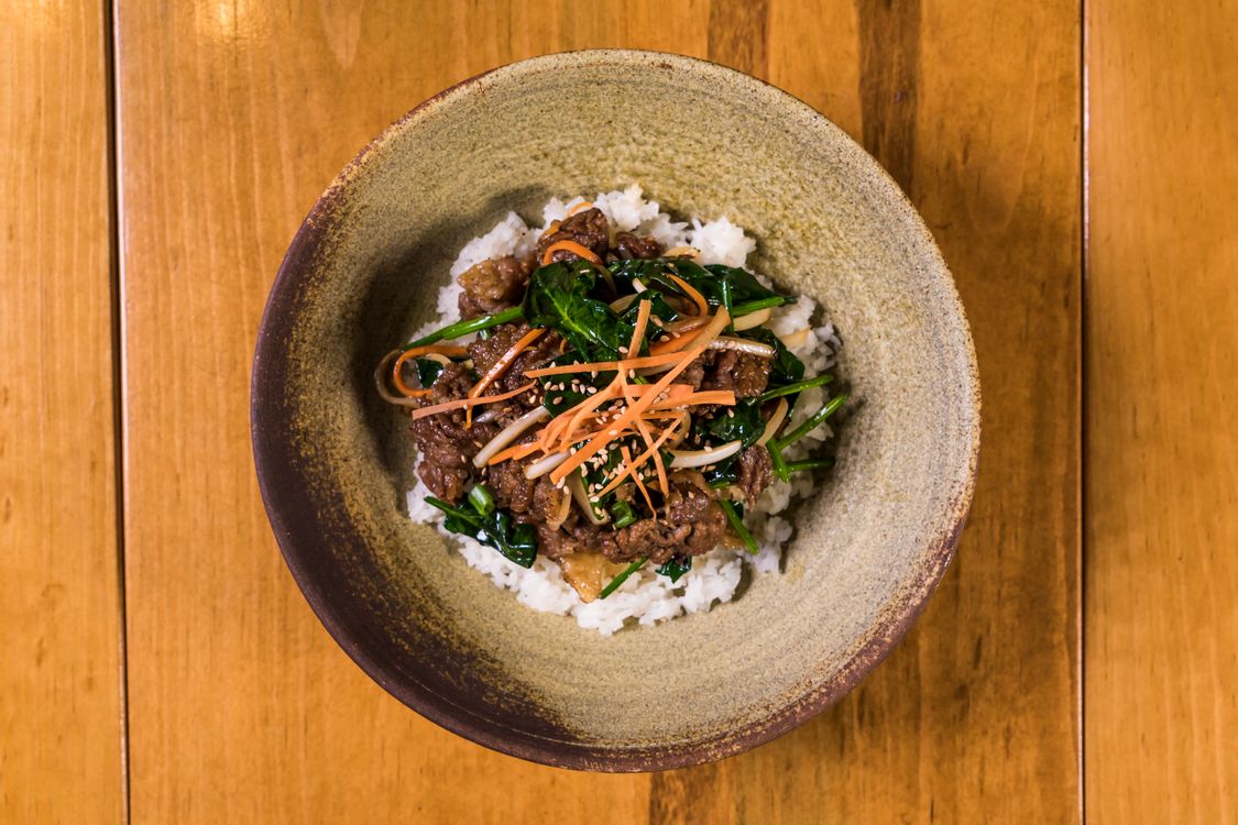 Korean bulgogi beef bowl with rice, shredded carrots, spinach, scallions, and sesame seeds