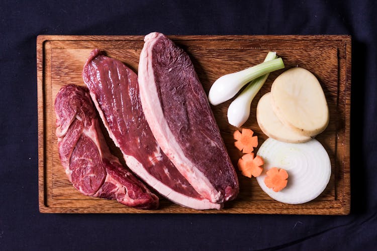 Sliced Raw Meat And Vegetables On Wooden Board