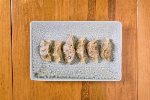 Free A set of six dumplings neatly arranged on a textured ceramic plate. Stock Photo