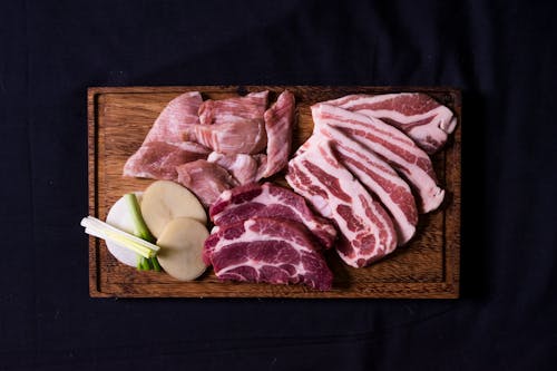 Close-Up Shot of Slices of Raw Meat on a Wooden Chopping Board