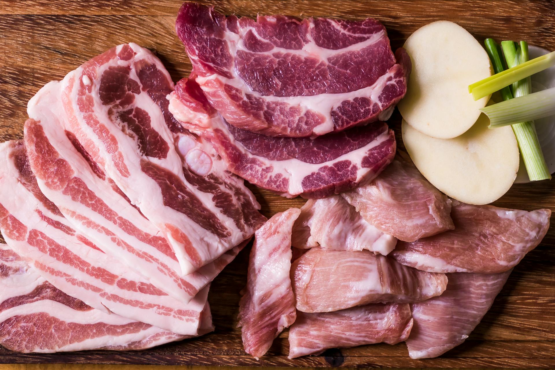 Close-Up Shot of Slices of Raw Meat on a Wooden Chopping Board