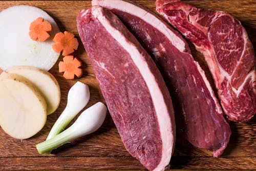 Free Close-Up Shot of Slices of Raw Meat on a Wooden Chopping Board Stock Photo