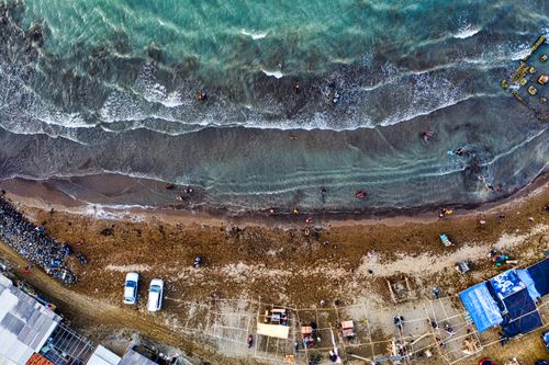 Free Top view of construction roofs and parked transport on rough shore against rippled sea in daylight Stock Photo