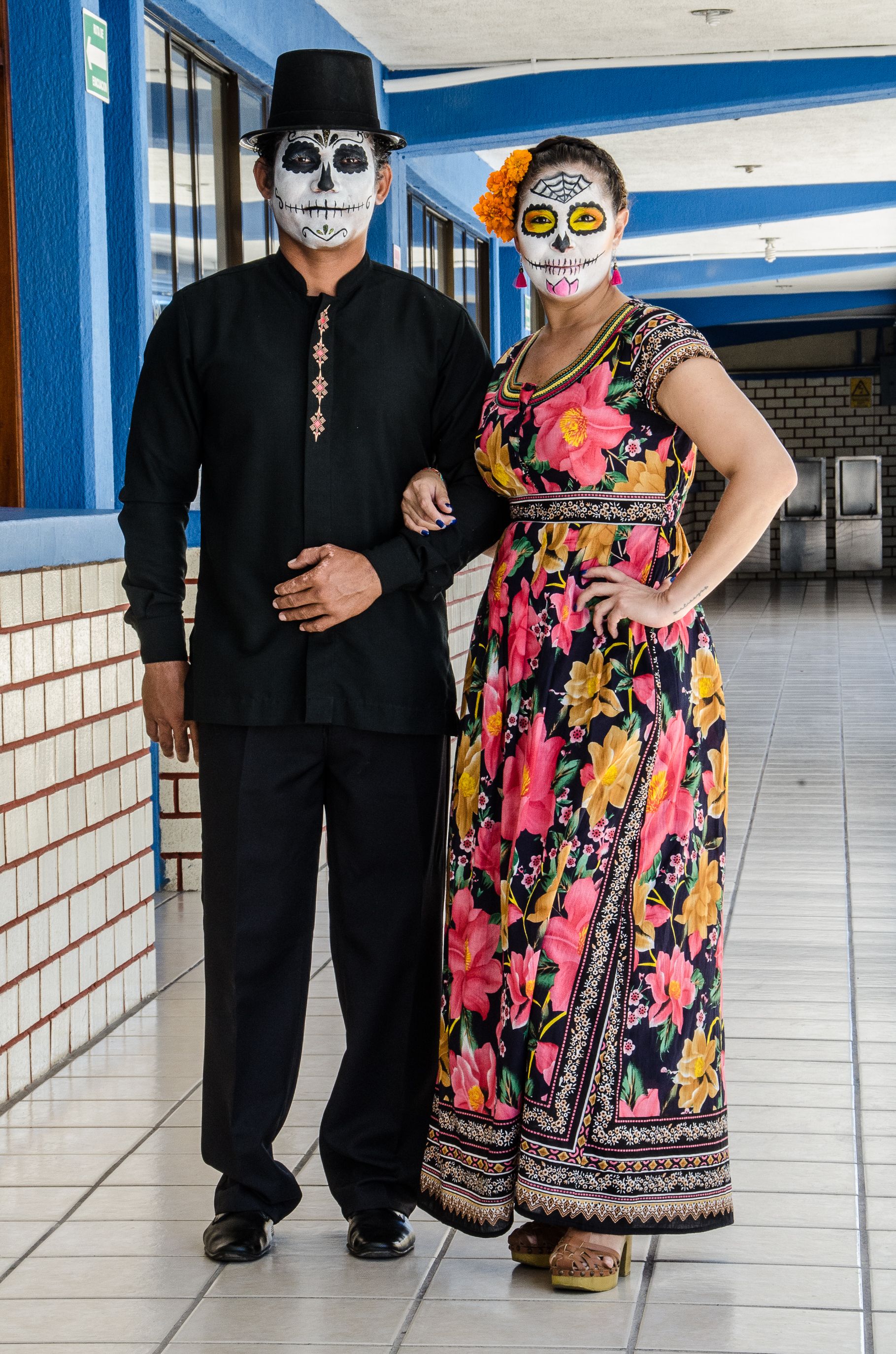 一对夫妇穿着传统的亡灵节服装，在走廊上涂着面漆