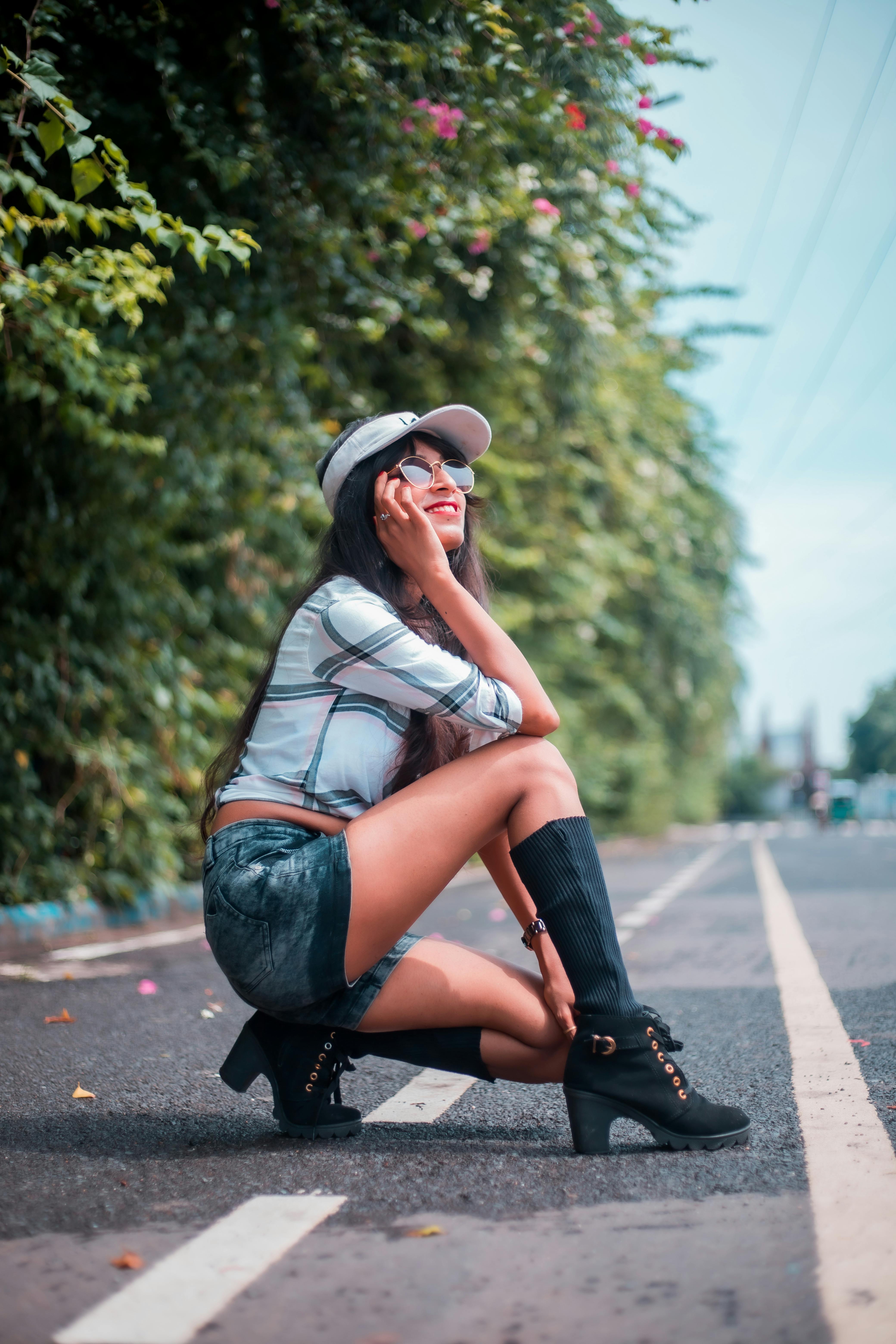 Woman in casual attire poses stylishly on a sunny road, capturing the essence of summer fashion.