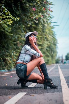 Woman in casual attire poses stylishly on a sunny road, capturing the essence of summer fashion.