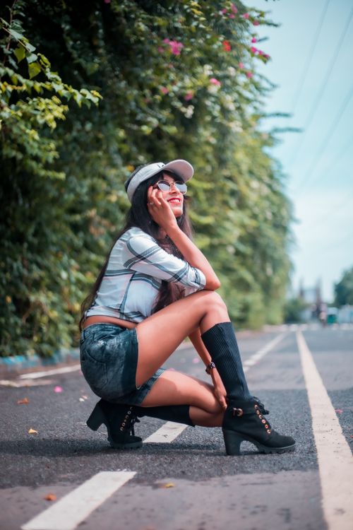 Free Woman in casual attire poses stylishly on a sunny road, capturing the essence of summer fashion. Stock Photo
