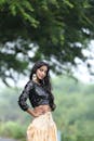 Woman in Black Long Sleeve Shirt Standing Near Green Tree