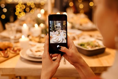 Free A festive holiday dinner table is photographed using a smartphone, capturing a warm Christmas atmosphere. Stock Photo