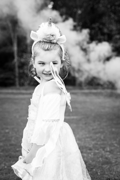 Free Charming portrait of a young girl in a unicorn costume smiling in a black-and-white photo. Stock Photo