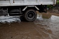 Old transport with rusty surface on roadway with rippled puddle and mud in daylight
