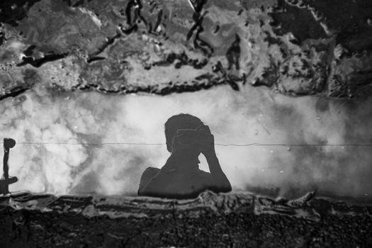 Unrecognizable photographer taking photo of puddle on camera