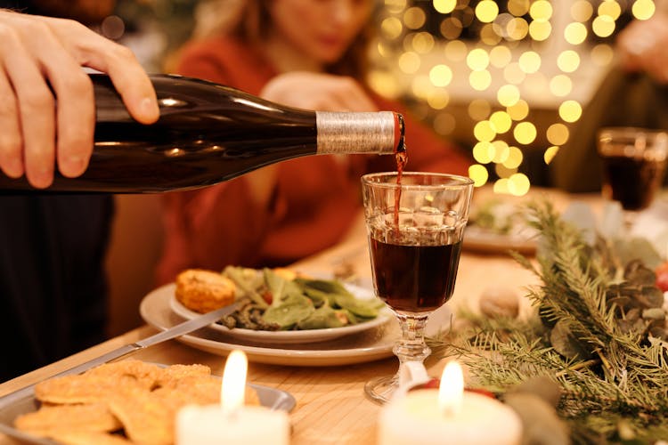 Person Pouring Wine On Clear Drinking Glass