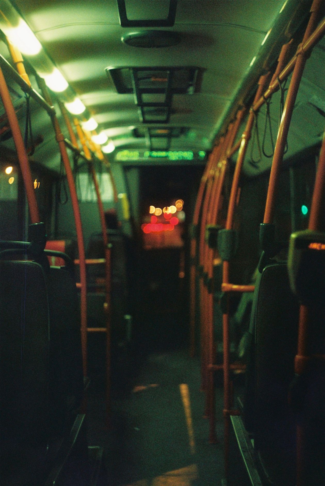 Empty bus interior glowing at night, seats and handrails lit while city lights blur past the windows