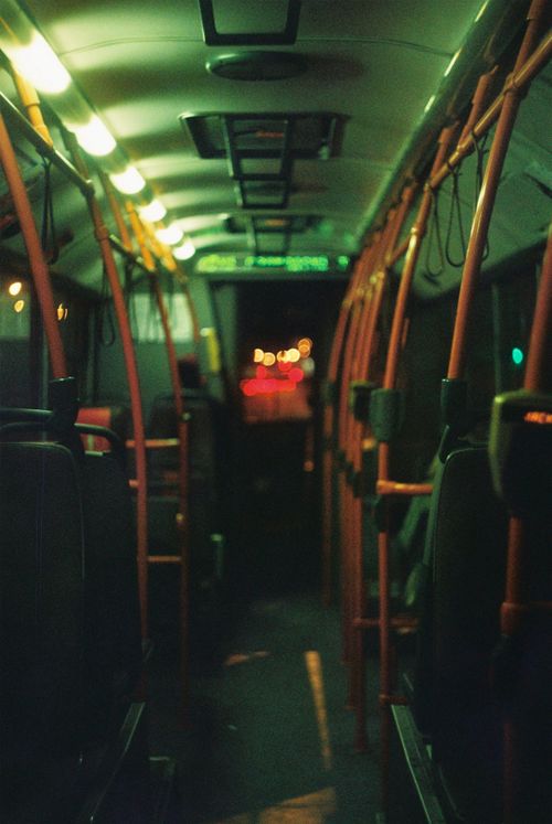 Free A moody interior view of a public bus at night, showcasing neon lights and empty seats. Stock Photo