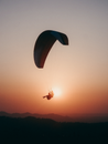 Paraglider flying in sunset sky