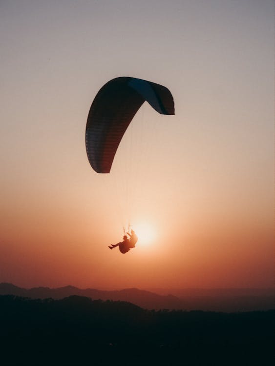 Paraglider flying in sunset sky