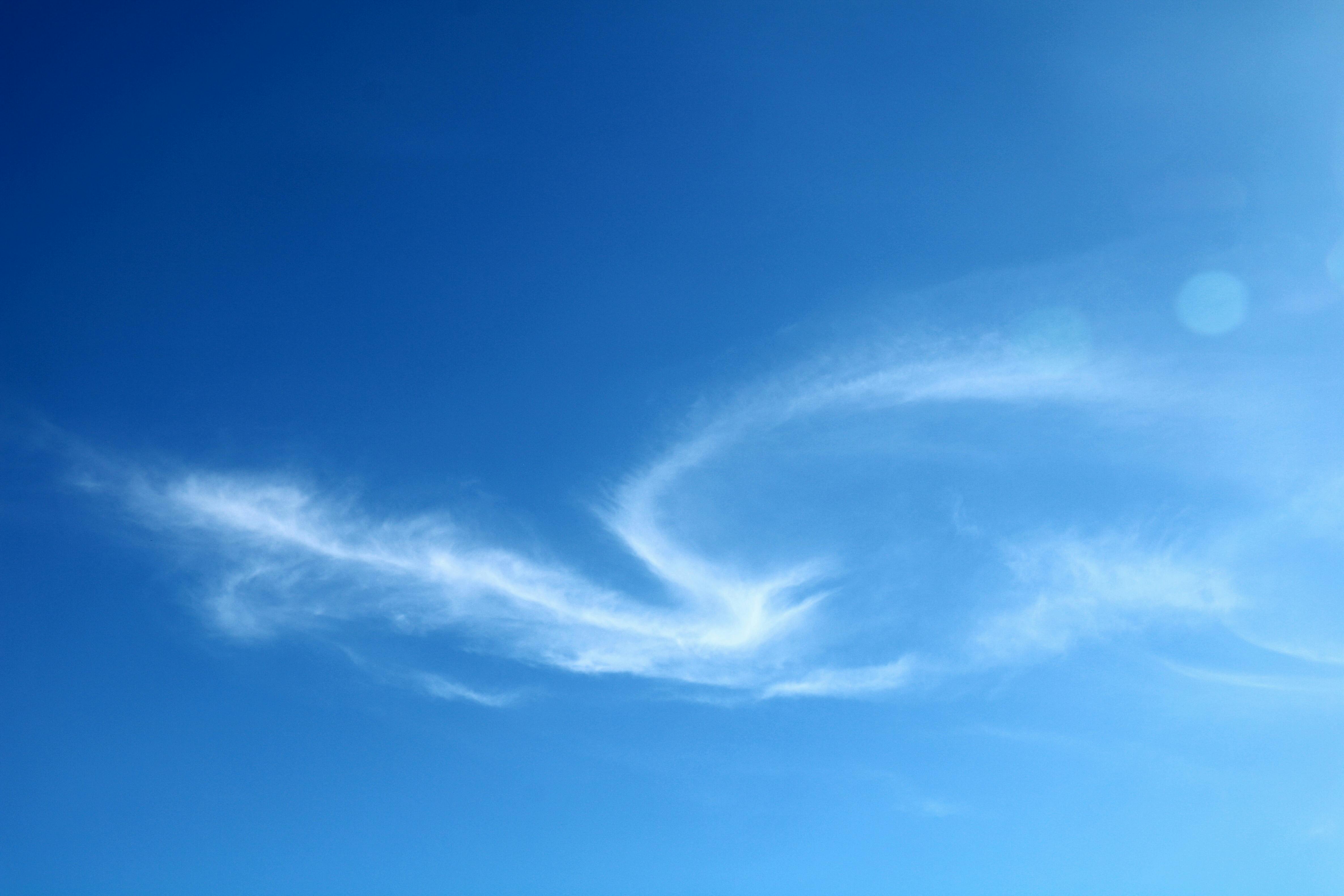 A clear blue sky featuring elegant, wispy cirrus clouds on a sunny day.