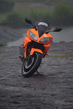 一辆充满活力的橙色运动自行车停在雨天潮湿的土路上