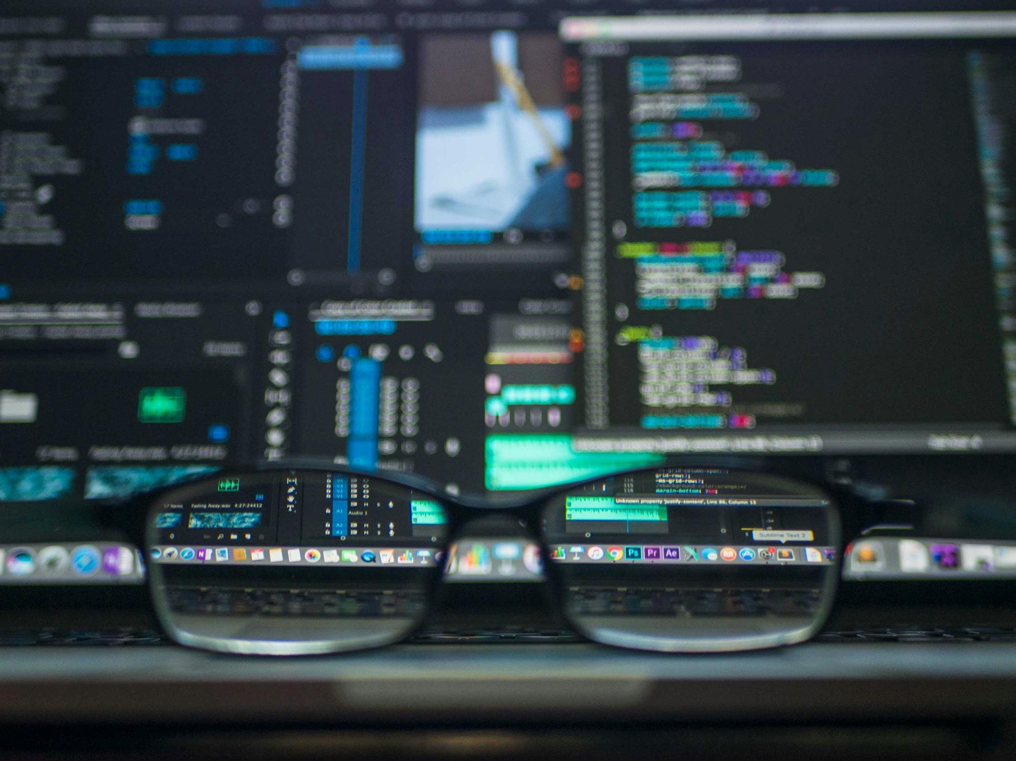 Pair of glasses in front of computer screen depicting complicated series of data. 