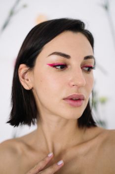 Close-up portrait of a woman showcasing bold pink eye makeup and minimalist style.