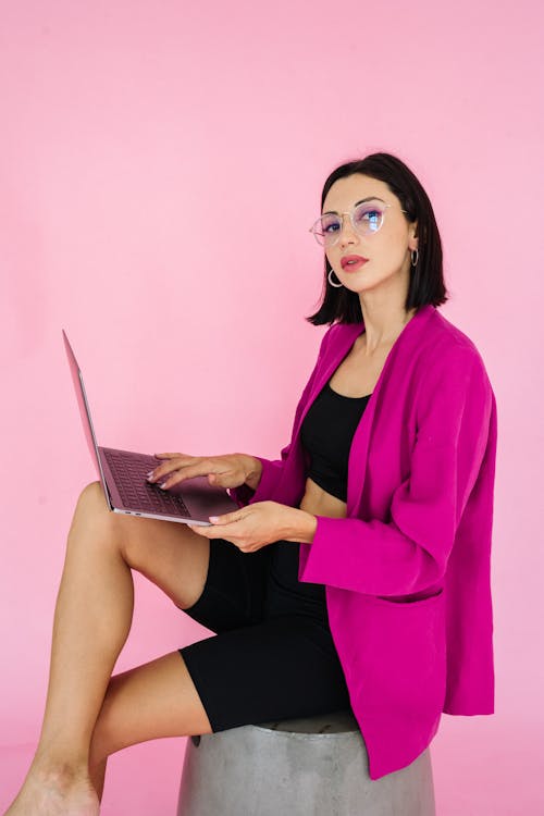 Vrouw In Roze Blazer En Zwarte Jurk Zittend Op De Vloer Met Laptopcomputer