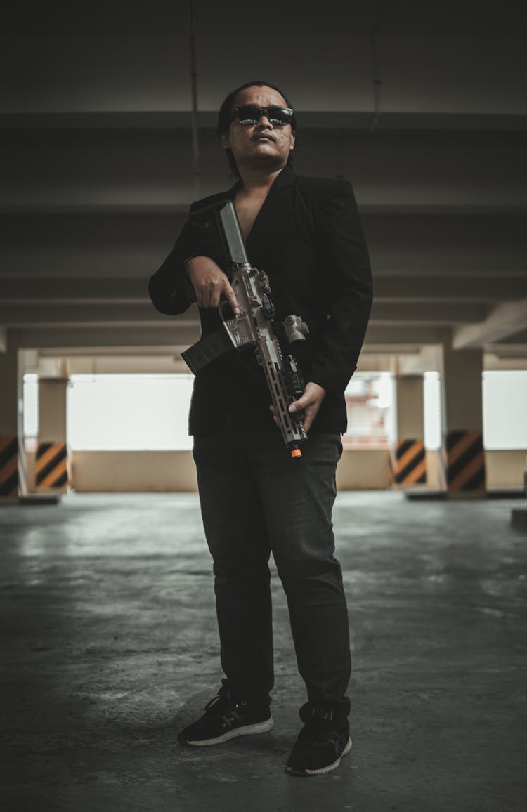 Low Angle View Of A Man With Machine Gun In A Garage 