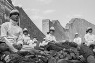 A Grayscale Photo of People Sitting on Rocks while Wearing Blindfolds