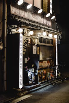 Cozy traditional Japanese street eatery with bicycle in Kyoto, Japan, illuminated at night.