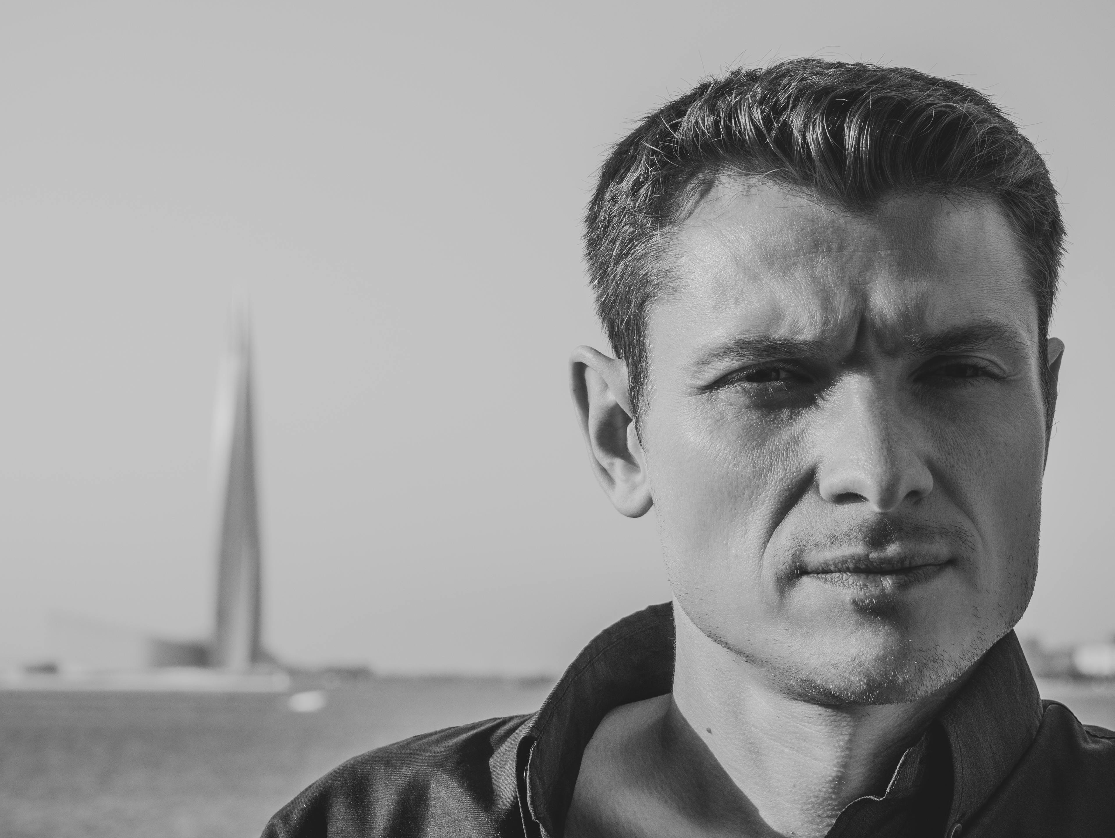 Grayscale portrait of a man with a cityscape in the background, conveying a contemplative expression.
