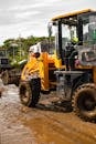 Unrecognizable driver in tractor on dirty road under cloudy sky