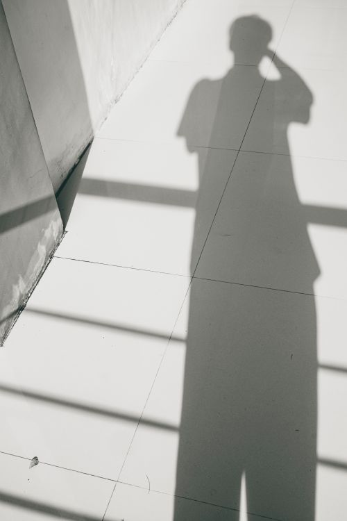 Free From above black and white back view of unrecognizable male shade on tiles on sunny day Stock Photo