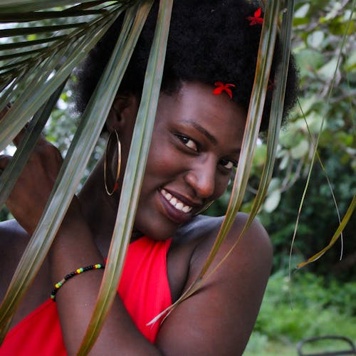 Woman in Red Tank Top Smiling Under the Coconut Leaves