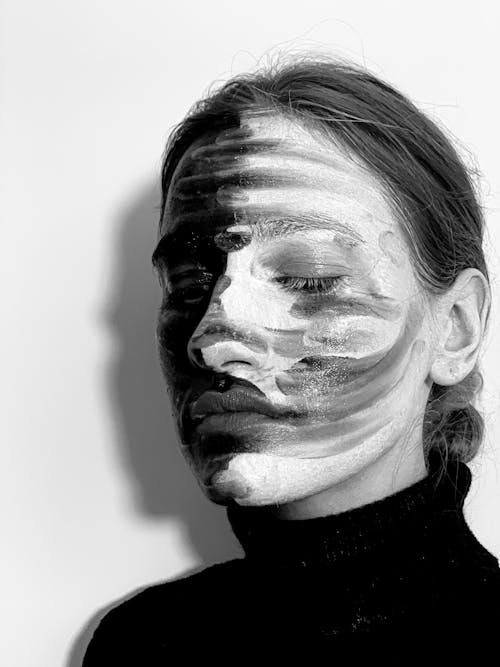 Contemplative young woman with painted face looking down