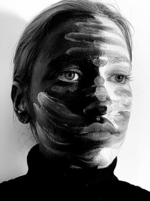 Free Black and white of serious young woman with dark and light dyes on face looking away pensively in studio Stock Photo