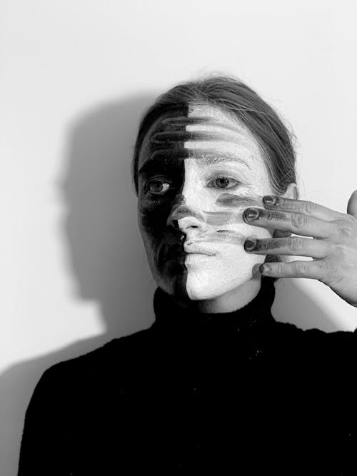 Black and white of emotionless female with body art on face looking away on white background