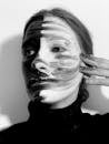From below black and white of weird disappointed female smearing greasepaint on face with messy hand while looking away on white background