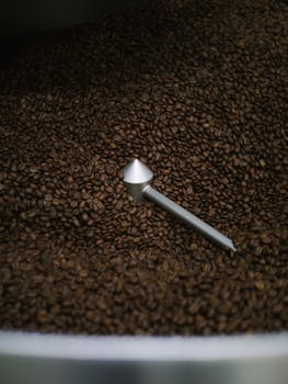 Close-up of aromatic coffee beans with a metal stirrer in a roasting machine.