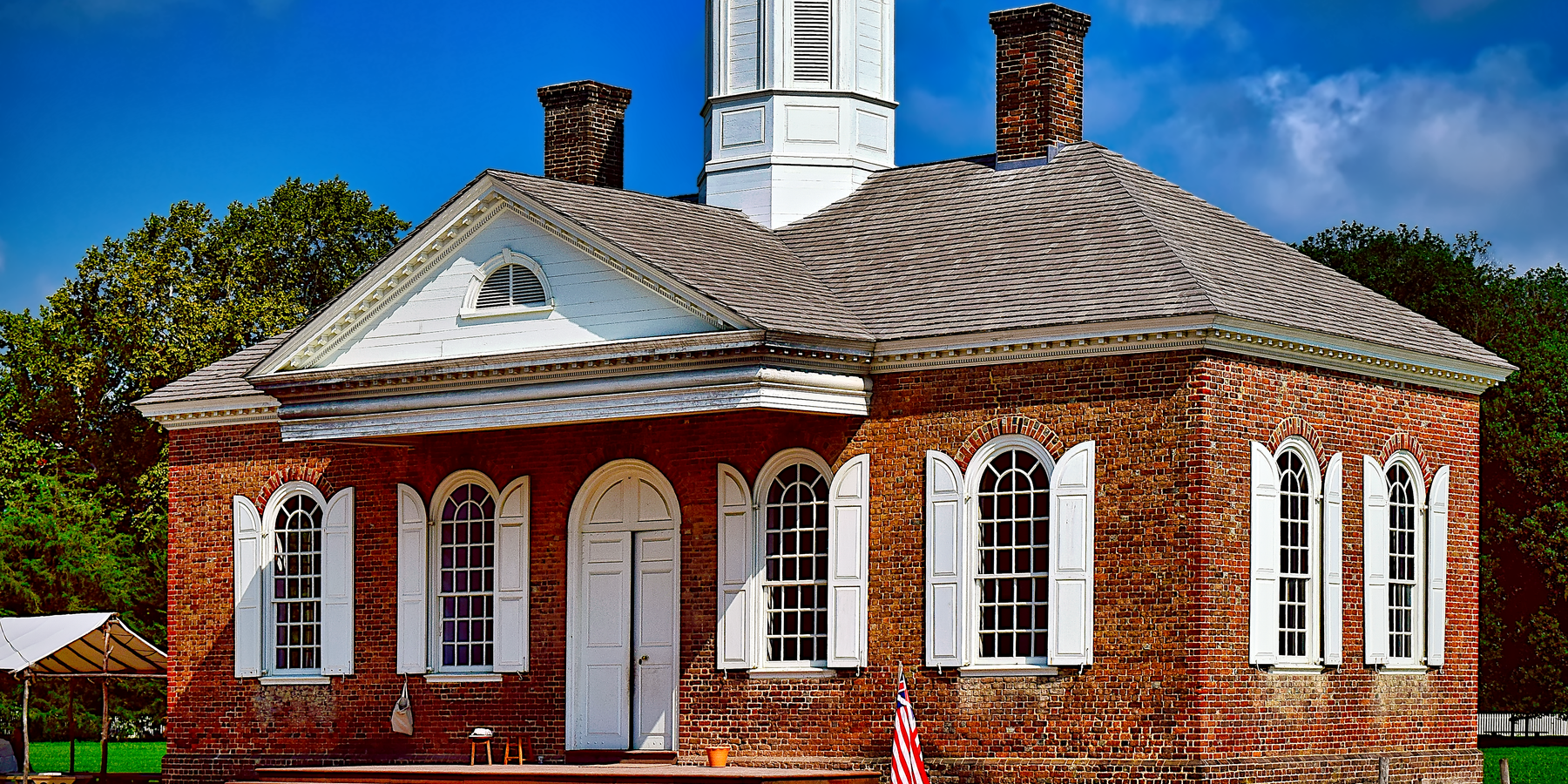 Colonial-style brick building with shutters and cupola in Williamsburg, USA.
