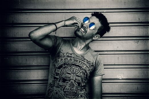 Fashionable man modeling sunglasses in an edgy urban setting.