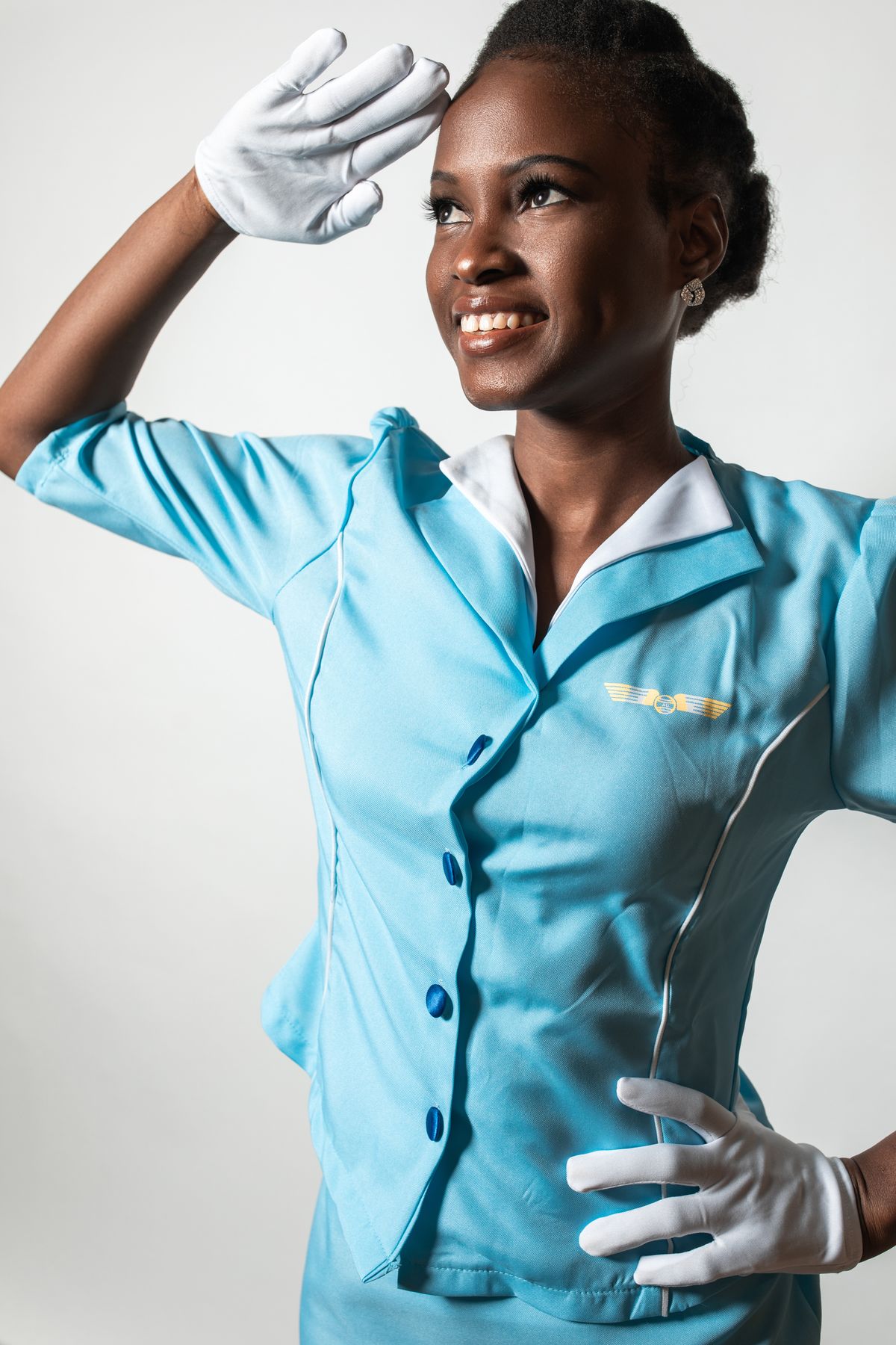 Real flight attendant in blue uniform saluting, professional portrait
