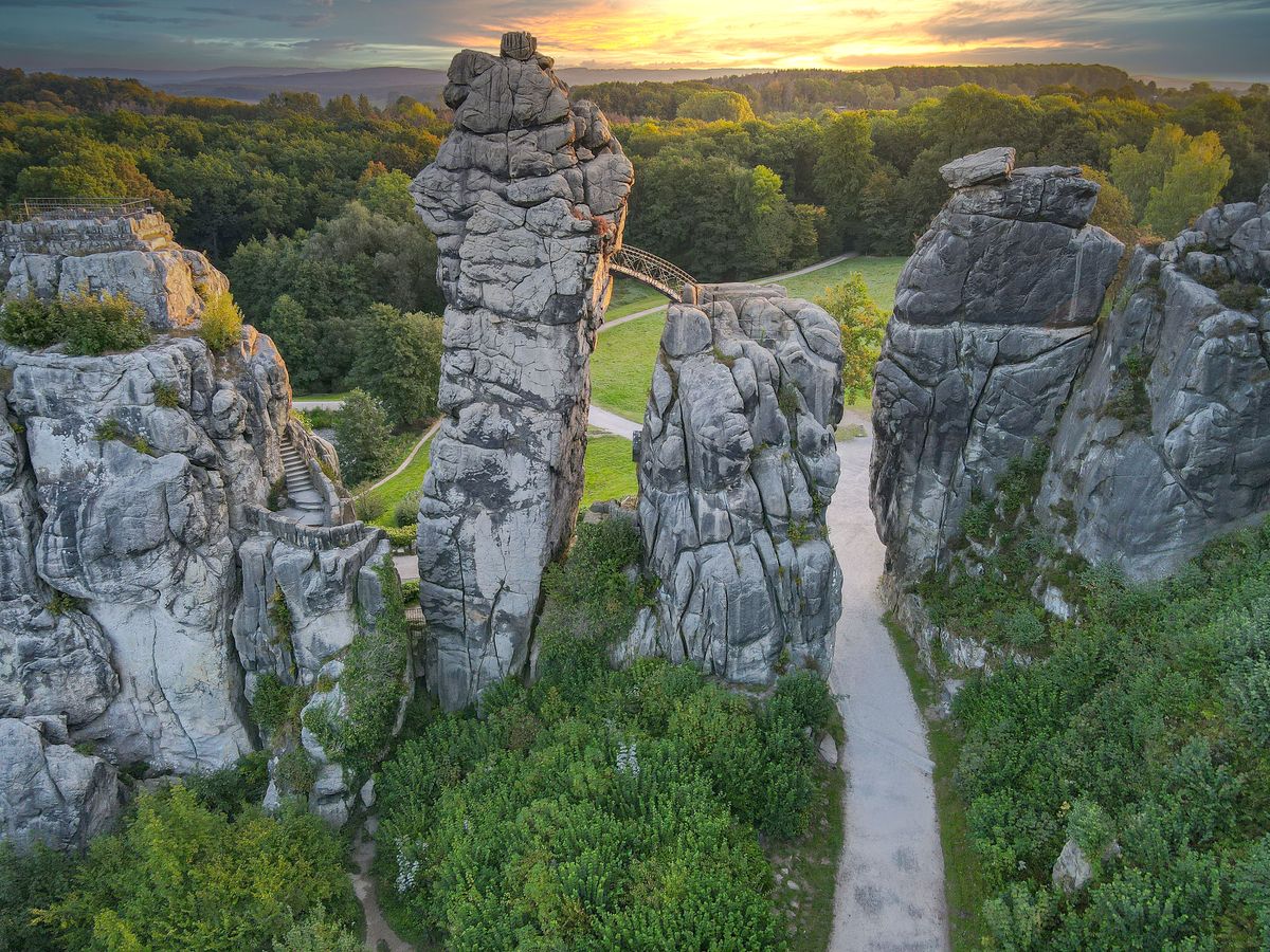 Formațiuni stâncoase cenușii pe un câmp verde, lângă pădure
