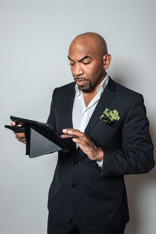 A Man in Black Suit Jacket Using a Black Tablet