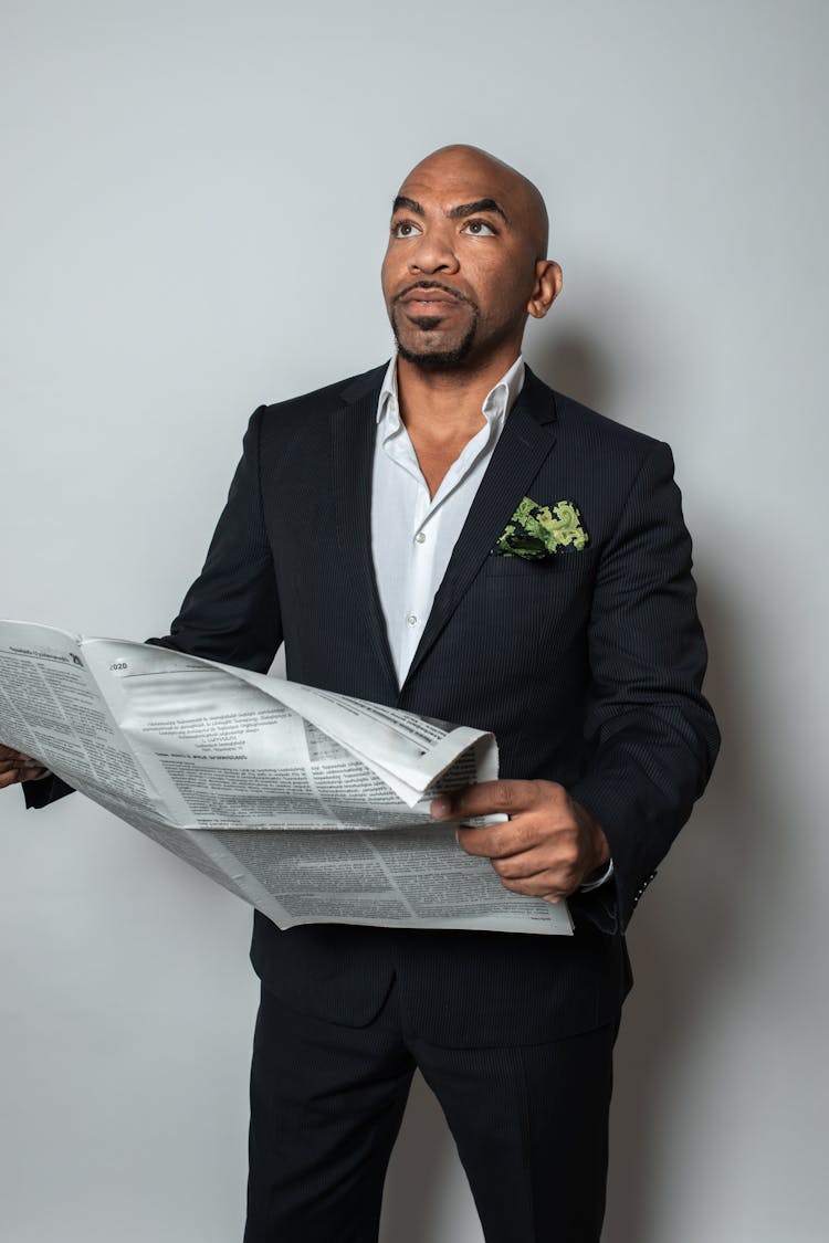 A Man In Black Suit Holding A Newspaper