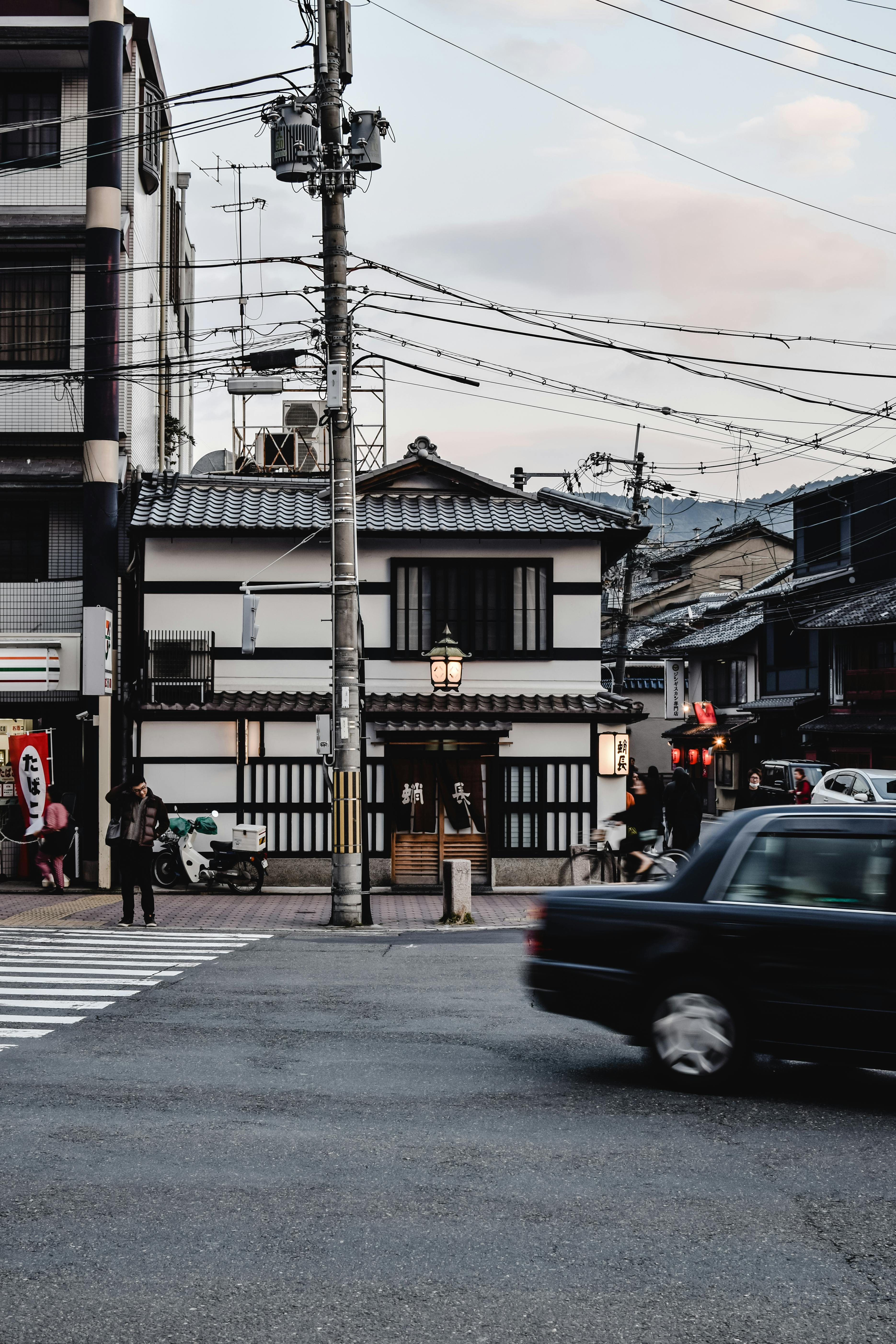 黄昏时分，日本京都繁华的街道上，传统建筑与过往车辆相映成趣